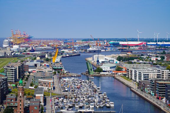 Panoramablick auf einen Hafen mit mehreren Schiffen und einem grünen Ufer.