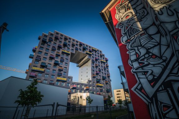 Moderne Wohnarchitektur mit bunten Balkonen und einer großen quadratischen Öffnung.